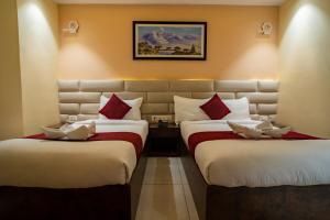 two beds in a hotel room with red and white pillows at Hotel Ozone 24 in Butwāl