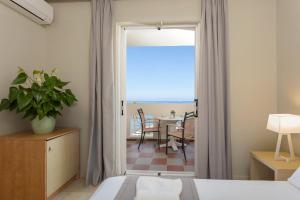 sypialnia z drzwiami prowadzącymi na patio ze stołem w obiekcie Xenos Kamara Beach w Argasio