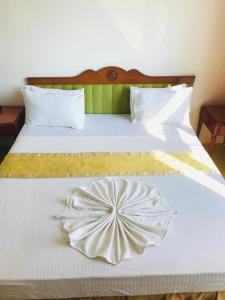 ein Bett mit einer weißen Tagesdecke mit einer Blume darauf in der Unterkunft Hotel Dream Paradise in Ja-Ela