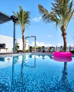 a swimming pool with palm trees and a pink float at Al Dana Paradise Luxury Villas Palm Fujairah Sea View in Fujairah