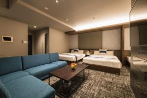 pokój hotelowy z 2 łóżkami i niebieską kanapą w obiekcie GRAND BASE Kagoshima Tenmonkan w mieście Kagoshima