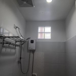 ein weißes Bad mit einer Dusche und einem Fenster in der Unterkunft Susing Seaside Guesthouse in Moalboal