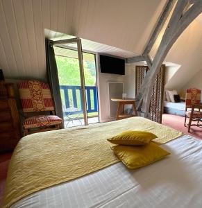Un dormitorio con una cama con almohadas amarillas. en Logis Hôtel Le Manoir Des Portes, en Lamballe