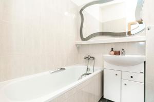 a bathroom with a white tub and a sink at ALURE RESIDENCES 3 & 24h self check-in, parking in the garage in the apartment building included, new building, terrace, green location with a forest park with a lake, children's playground in Banská Bystrica +14 photos