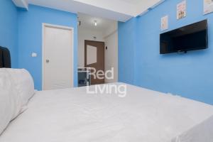 a bedroom with a bed and a tv on a blue wall at RedLiving Apartemen Podomoro Golf View - Room 37 Tower Balsa in Taladjurg-udik +17 photos