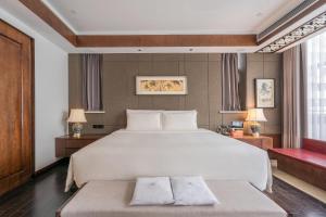 a bedroom with a large white bed and a red bench at Atour X Chongqing Jiefangbei pedestrian Street in Chongqing