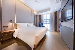 um quarto de hotel com uma grande cama branca e uma televisão em Atour Hotel Xiamen Jimei Lake Business Center em Xiamen
