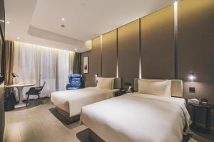 上海市にあるAtour Hotel North Bund Shanghaiのベッド2台とデスクが備わるホテルルームです。