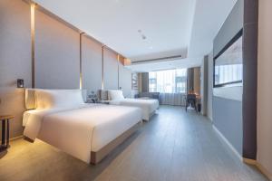 a hotel room with two beds and a desk at Atour Hotel Haikou East High-Speed Railway Station Xueyuan Road in Pin-lien