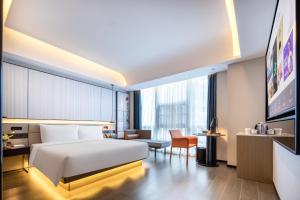 深セン市にあるAtour S Hotel Shenzhen Futian Portのベッドと椅子付きのホテルルーム