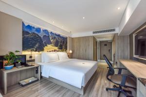 a bedroom with a large white bed and a desk at Atour Hotel Guiyang Convention and Exhibition Center in Guiyang