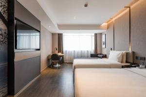 Atour Hotel Hangzhou Xiaoshan Airport في Xiaoshan: غرفة فندقية بسريرين ومكتب