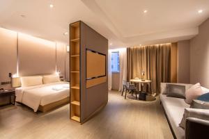 Atour Hotel Zhengzhou Xinzheng International Airport في تشنغتشو: غرفه فندقيه بسرير واريكه