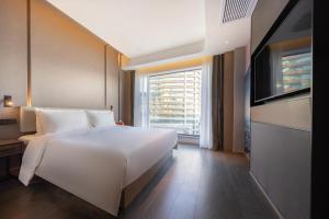 a large white bed in a room with a large window at Atour Hotel Kunming International Trade Center in Kunming