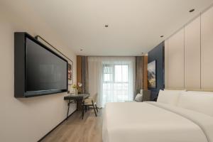 Atour Hotel Fuzhou Jinshan Aegean Sea في فوتشو: غرفة فندقية بسرير وتلفزيون بشاشة مسطحة