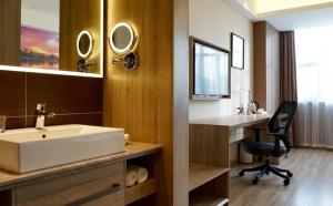 La salle de bains est pourvue d'un lavabo et d'un bureau avec une chaise. dans l'établissement Atour Hotel Tianjin Binhai Second Avenue Branch, à Binhai