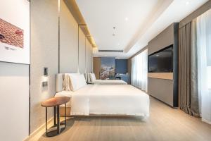 a bedroom with a large white bed and a stool at Atour Hotel Chengdu Wenshufang in Chengdu +34 photos