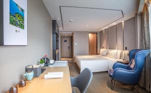廈門市にあるAtour Hotel Xiamen Huandao South Roadのベッドとデスクが備わるホテルルームです。