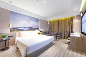 um quarto de hotel com uma cama e uma televisão em Atour Hotel Yingxiongshan Road Jinan em Jinan