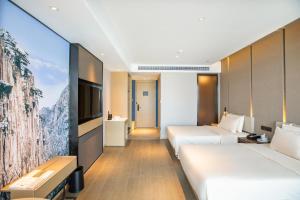 ein Hotelzimmer mit 2 Betten und einem TV in der Unterkunft Atour Hotel Huangshan Tunxi Old Street Xin an River in Huangshan Scenic Area