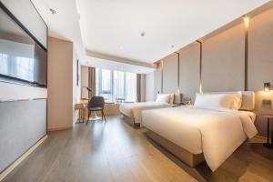 Atour Hotel Kunming Hi-tech Wuyue Plaza في كونمينغ: غرفة فندقية بسريرين ومكتب