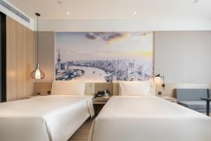 duas camas num quarto de hotel com um quadro na parede em Atour Light Hotel Jinan International Covention Centre em Jinan