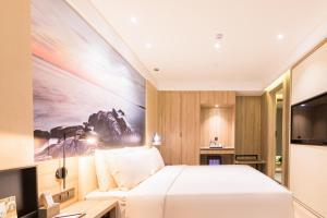 a bedroom with a bed and a large painting on the wall at Atour Hotel Weihai City Center in Weihai