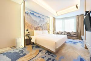 um quarto com uma grande cama branca e um sofá em Atour Hotel Railway Station Dalian em Dalian