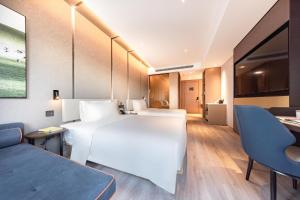 a hotel room with a large white bed and a couch at Atour Hotel Tianjin Marina Third Street MSD in Binhai