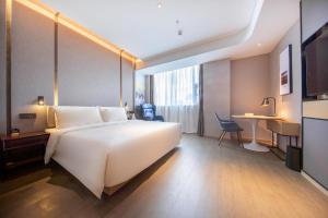 Habitación de hotel con cama blanca grande y escritorio. en Atour Hotel Shenzhen Huaqiang North, en Shenzhen