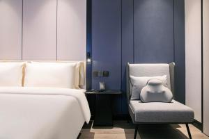 a bedroom with two beds and a chair with a pillow at Atour X Hotel Hangzhou West Lake Wulin Plaza Yan'an Road in Hangzhou