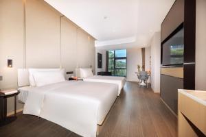上海市にあるAtour Hotel Shanghai Wujiaochang Daxue Roadのベッド2台とテレビが備わるホテルルームです。