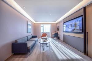 a living room with a couch and a flat screen tv at Atour Hotel Tianjin Marina Third Street MSD in Binhai