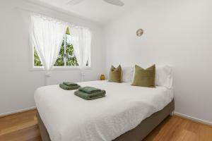 サフォーク・パークにあるSuffolk Park Palms - Relaxing home minutes to Byronの白いベッドルーム(緑のタオルが付いたベッド付)