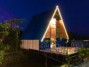 una casa con techo triangular por la noche en LA'S FARMSTAY, en Tây Ninh