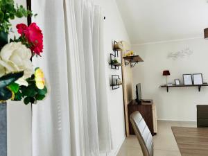 een kamer met een wit gordijn en een vaas met bloemen bij Assisi, Angolo di Matilde in Petrignano