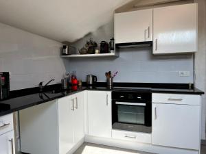 una cocina con armarios blancos y horno negro en Appartement Urrugne, 3 pièces, 5 personnes - FR-1-239-931 en Urrugne