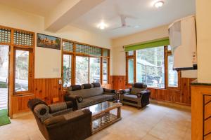 a living room with two couches and a tv at FabHotel Greenwoods Inn in Dharamshala