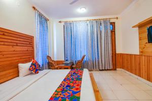 1 dormitorio con 1 cama, mesa y sillas en FabHotel Greenwoods Inn, en Dharamshala