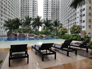 a pool in a building with chairs and palm trees at Mall of Asia Shore Dynastel Staycation in Manila