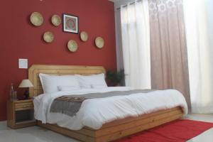 1 dormitorio con cama y pared roja en Junglaat Stays & Experiences en Dharamshala