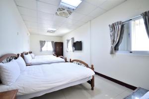 three beds in a room with white walls at Dongjin B&B in Taimali