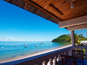a balcony with a view of a beach and boats in the water at Chambres d'hôtes Beluga in Nosy Be