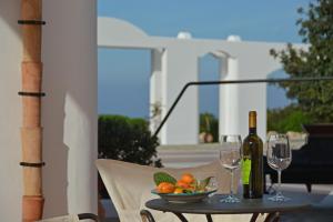 a table with a bowl of fruit and two wine glasses at Tenute Plaia Agriturismo in Scopello