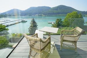 two chairs and a table on a balcony overlooking a lake at Amerika-Holzer Hotel & Resort in Sankt Kanzian