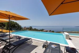 a swimming pool with chairs and an umbrella at DINORA Exclusive Apartments in Makarska