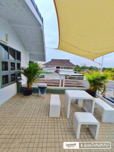 a patio with two white benches and an umbrella at บ้านสุขใจ อัมพวา in Samut Songkhram