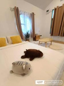 a stuffed dog laying on a bed in a bedroom at บ้านสุขใจ อัมพวา in Samut Songkhram