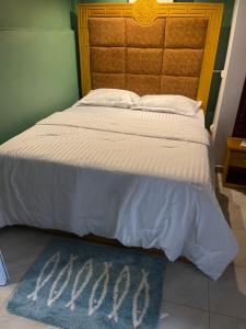 a bedroom with a bed with a blue rug next to it at Primier Mansion Guest Home in Limbe