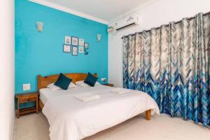 a bedroom with two beds and a blue wall at Cerca Del Mar in Calangute